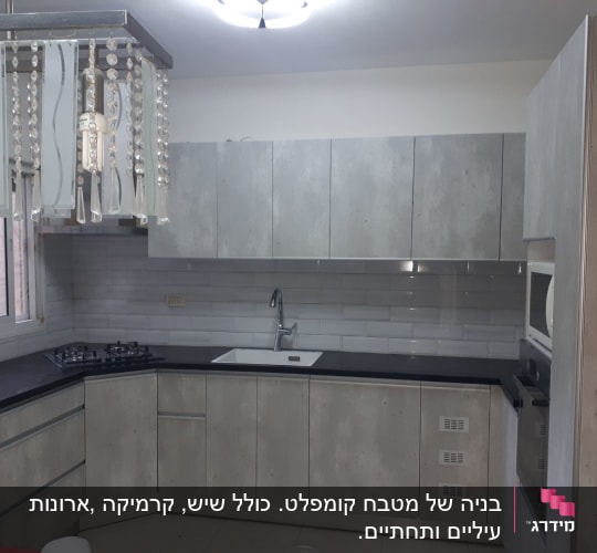 מטבח מודרני עם ארונות אפורים, כיור וכיריים.